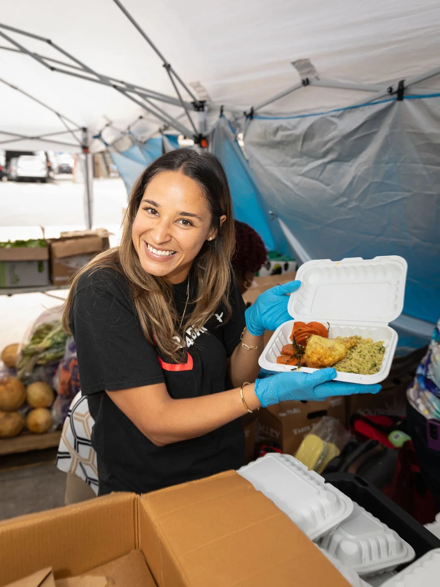 A volunteer handing off a meal box to a neighbor